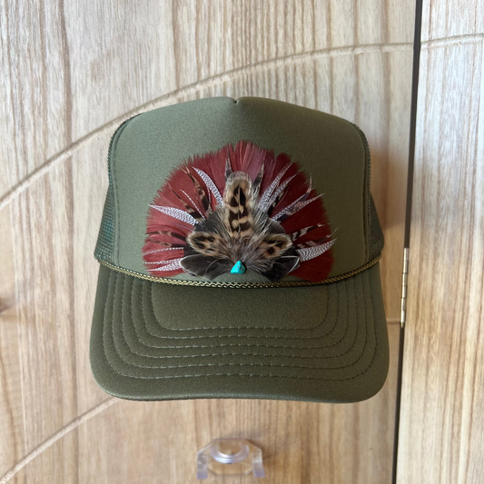Army Green trucker cap with a decorative pheasant mix feathers on a wooden surface