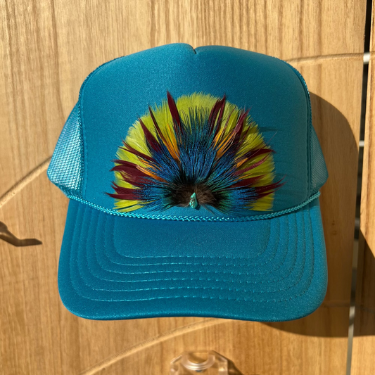 Blue cap with colorful feather design on a wooden surface