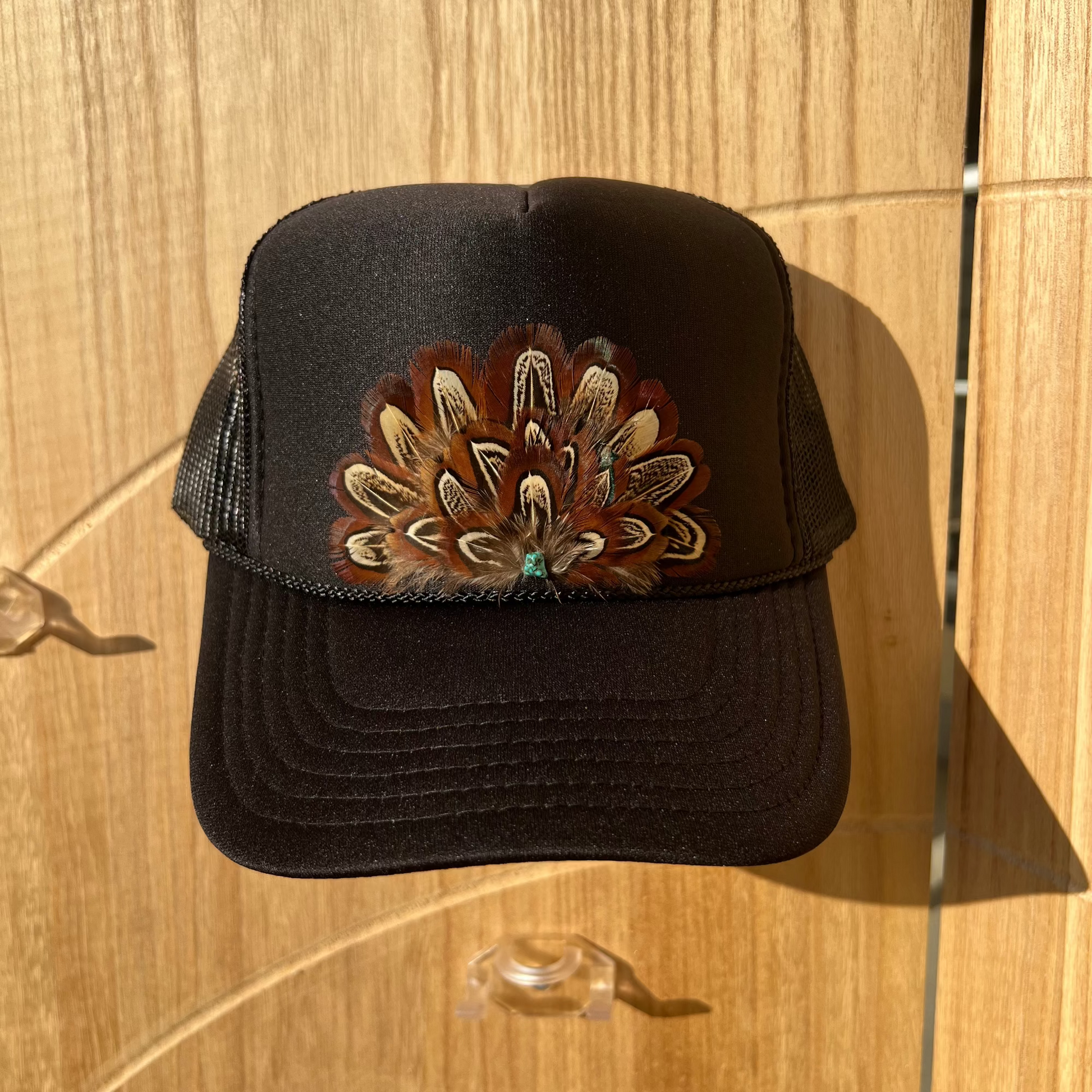 Black cap with a decorative flower emblem on a wooden surface