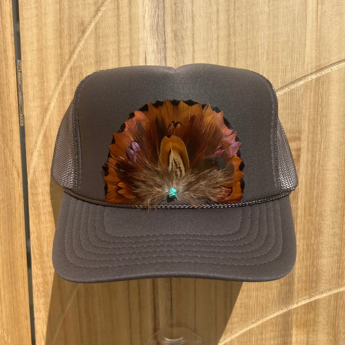 Gray cap with feather design on a wooden surface