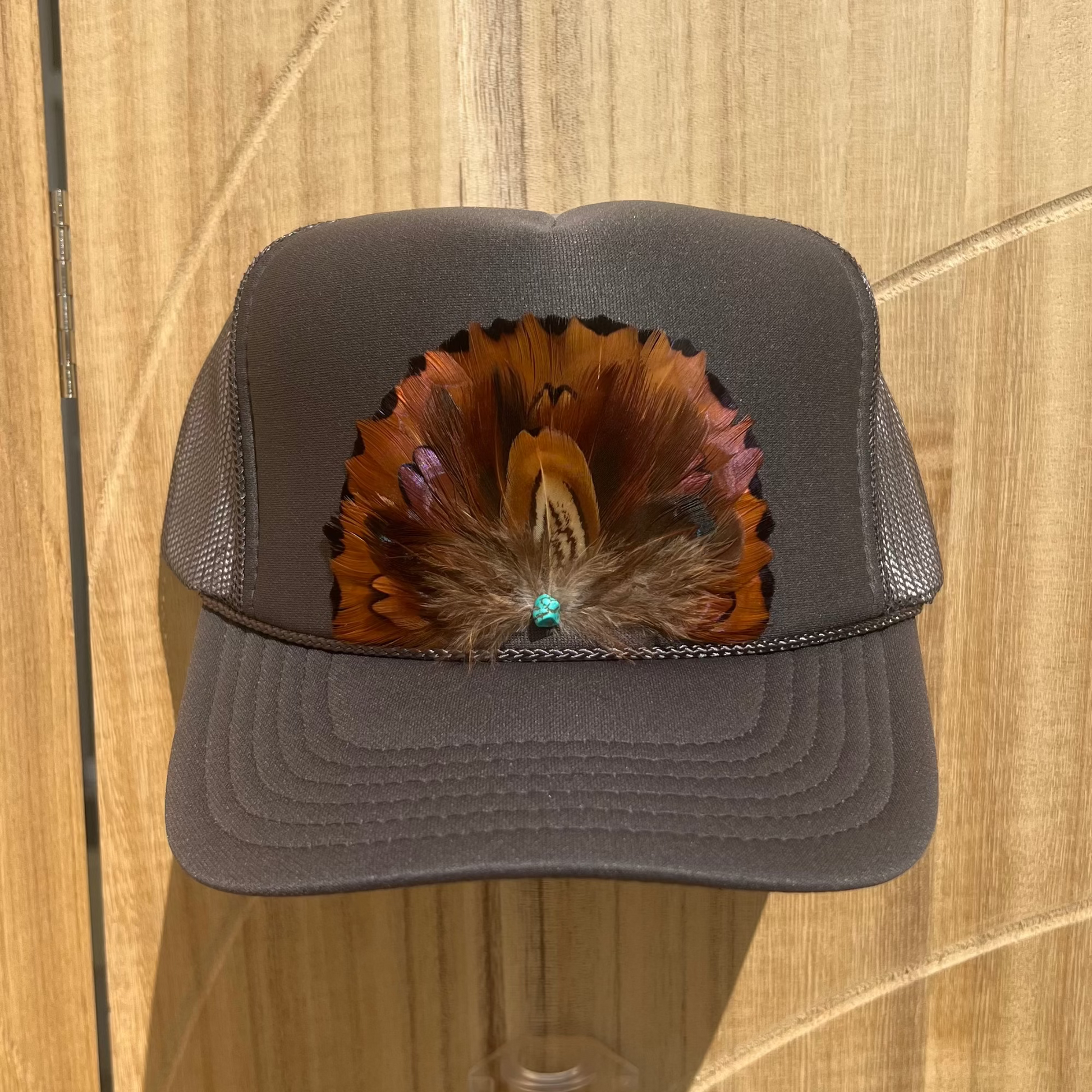 Gray cap with feather design on a wooden surface