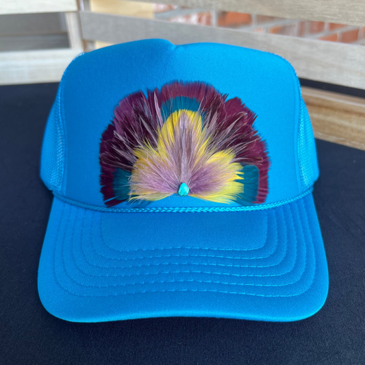 Blue cap with colorful feather design on a dark surface