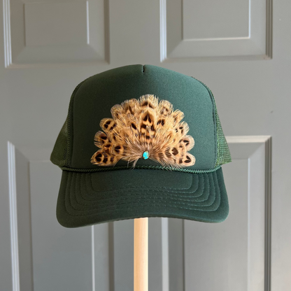 Front view of Volant Style trucker hat in hunter green featuring hand-placed tan brown feathers with a center turquoise stone.