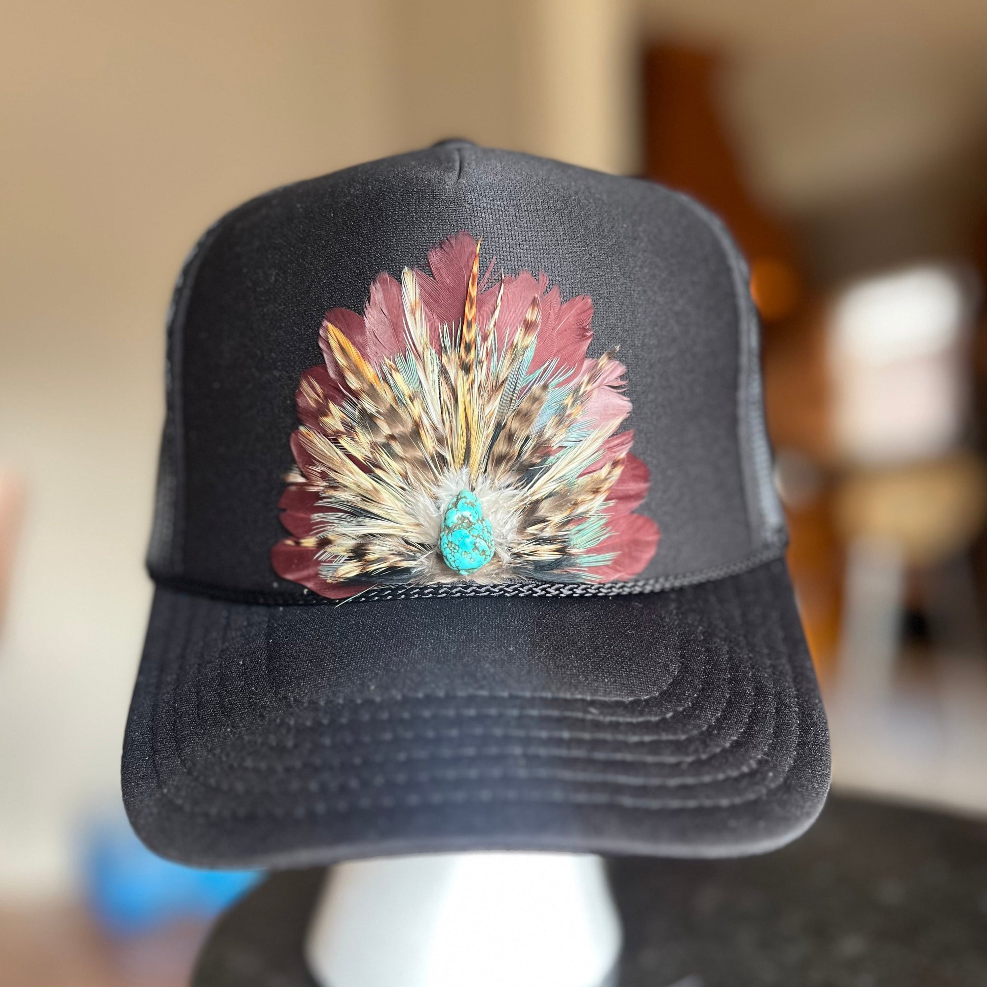 Black cap with a colorful feather design on a blurred background