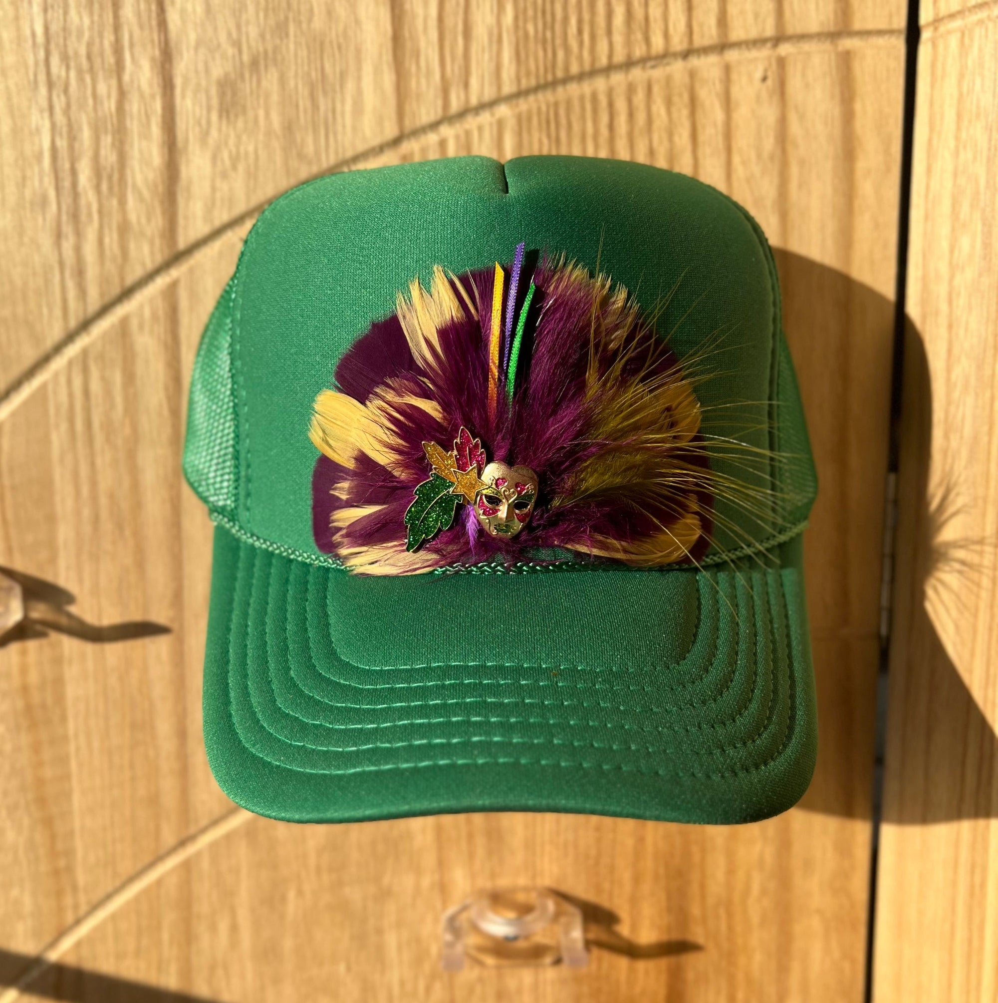 Green cap with colorful feather design on a wooden surface