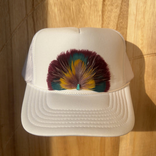 White cap with colorful feather design on a wooden surface